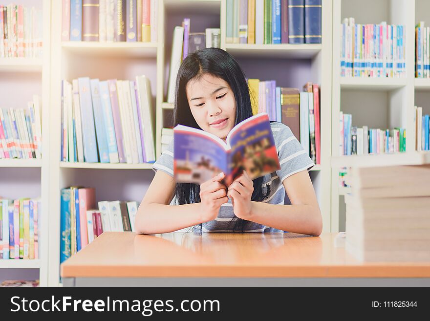 Portrait of clever Asian student reading and doing research in college library