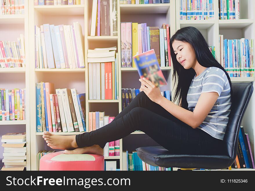 Portrait of clever Asian student reading and doing research in college library