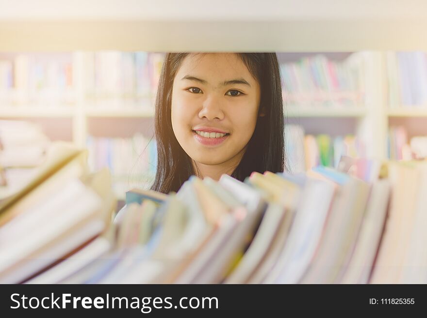 Portrait of clever Asian student reading and doing research in college library