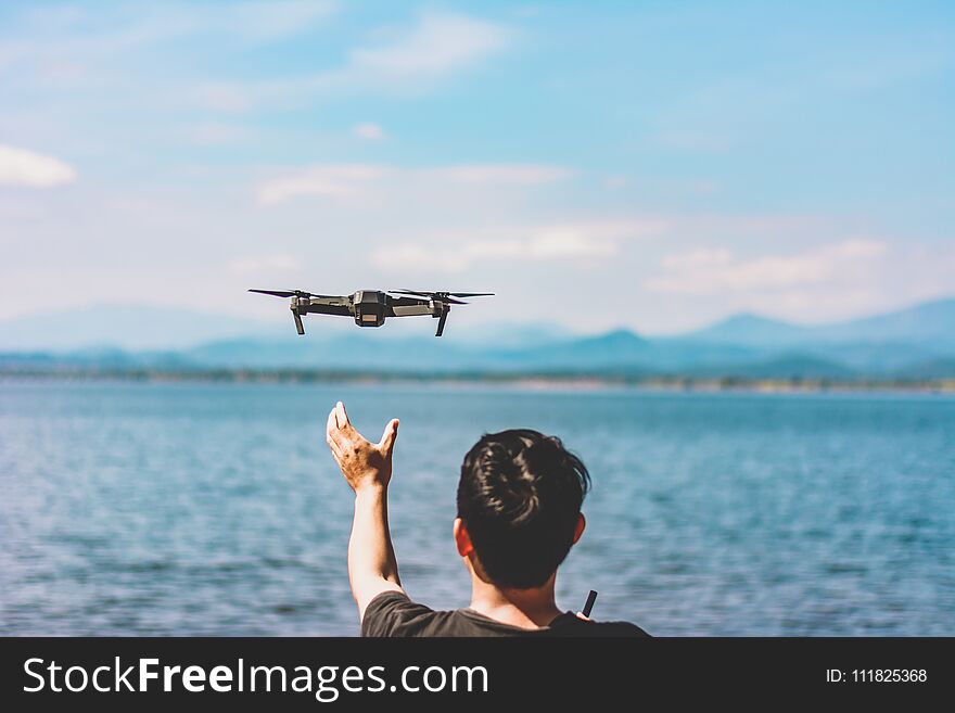 Man releasing flying drone quad copter with high resolution digital camera flying the sky with lake view