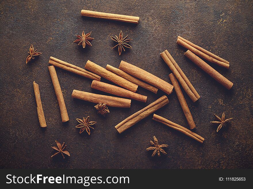 Cinnamon sticks and anise stars on the brown rusty backround top view.