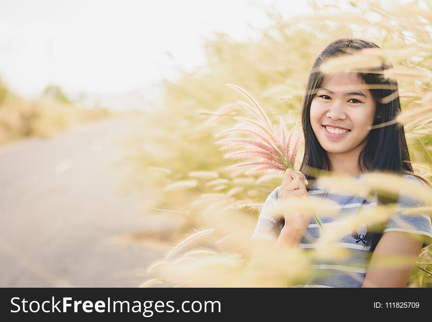 Woman enjoy grass flower in meadow at sunset