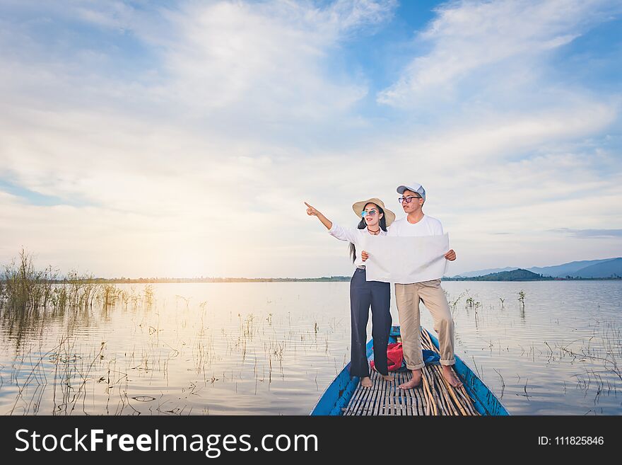 Travel men and women with mapk standing on tail of the boat with lake and mountain view, Travel concept. Travel men and women with mapk standing on tail of the boat with lake and mountain view, Travel concept