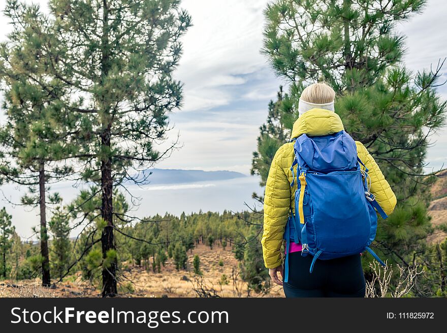Hiking woman with backpack looking at inspirational mountains landscape and woods. Fitness travel and healthy lifestyle outdoors in fall nature. Female backpacker tourist walking in forest.