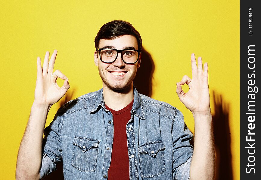 Portrait of a cheerful young man showing okay, studio shoot