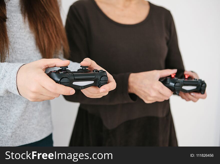 A young girl and an elderly woman play together in a video game. Joint pastime. Family life. Communication of the