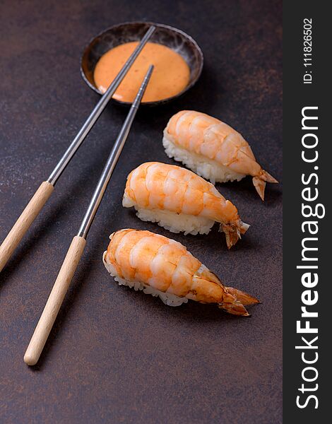 Nigiri sushi with shrimp and sauce on brown background