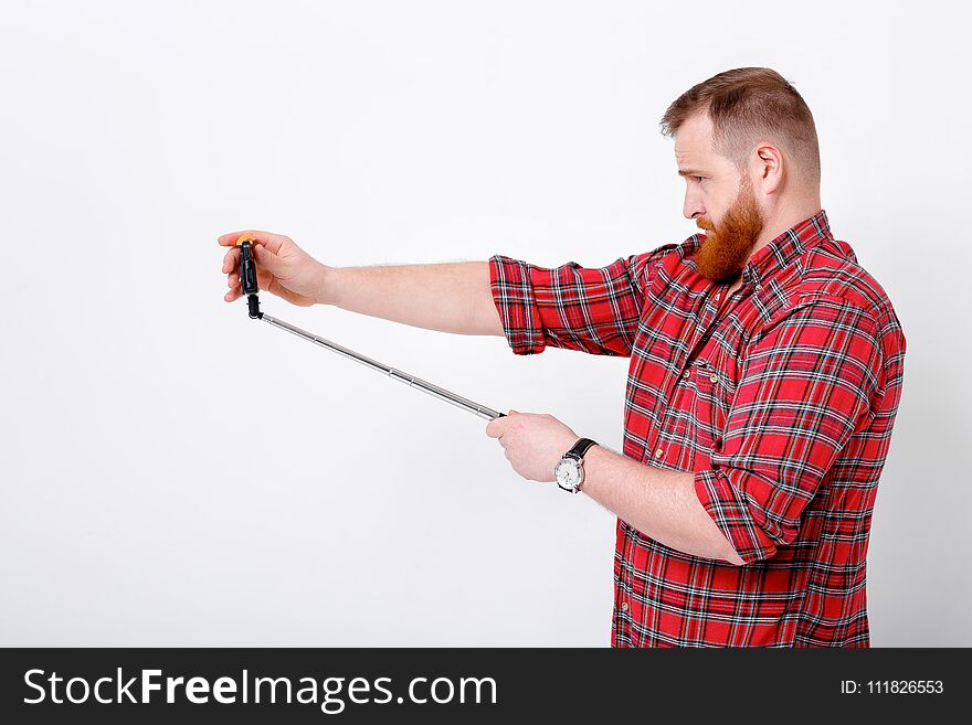 Man with red beard in plaid shirt makes selfie on phone. Man with red beard in plaid shirt makes selfie on phone