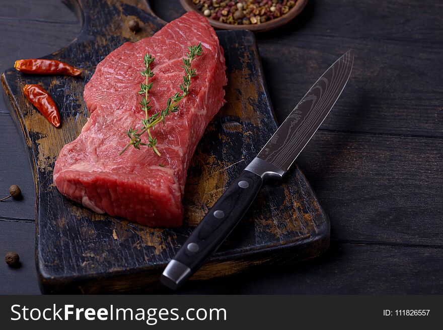 Raw beef steak with thyme and pepper and knife