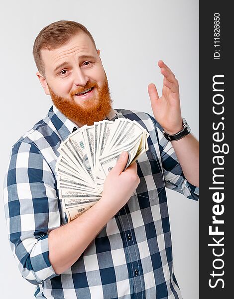 Young handsome smiling man with beard in plaid shirt holding a lot of hundred-dollar bills. money. Young handsome smiling man with beard in plaid shirt holding a lot of hundred-dollar bills. money