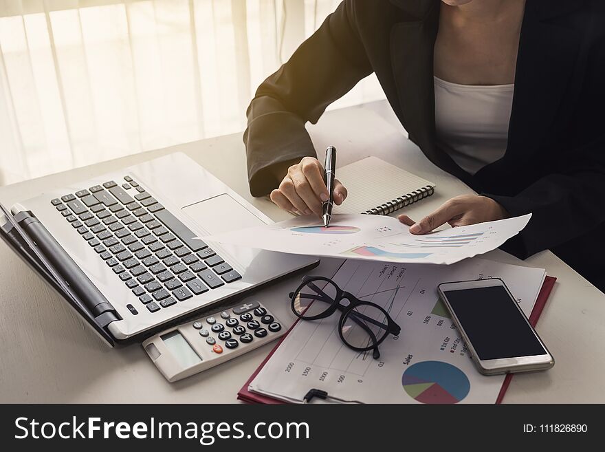 Businesswoman analyzing financial report with laptop