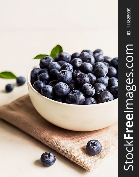 Juicy and fresh blueberries with green leaves on white bowl. Healthy eating