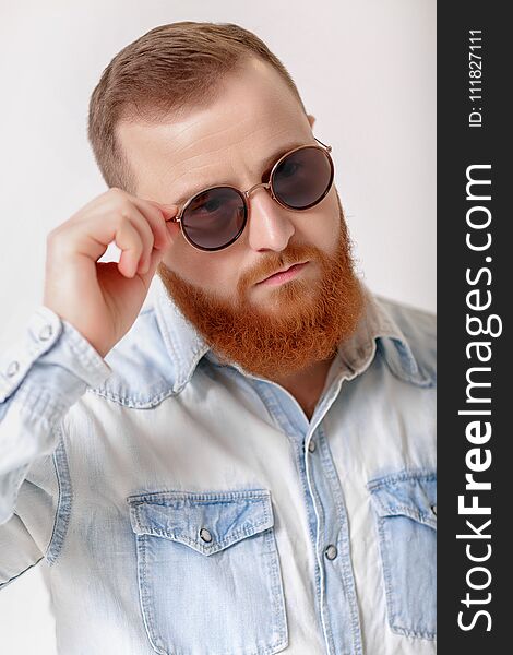 Close-up portrait of red-haired beard man in sunglasses and denim shirt