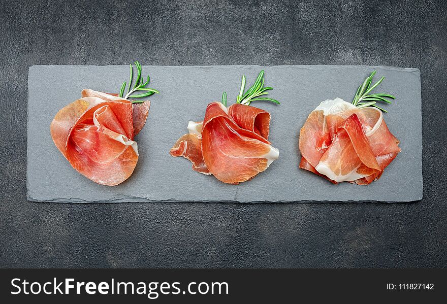 Italian prosciutto crudo or spanish jamon. Raw ham on stone cutting board. concrete background