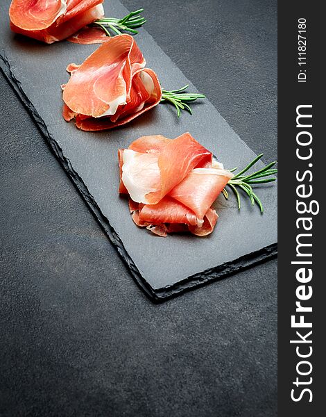Italian prosciutto crudo or spanish jamon. Raw ham on stone cutting board. concrete background