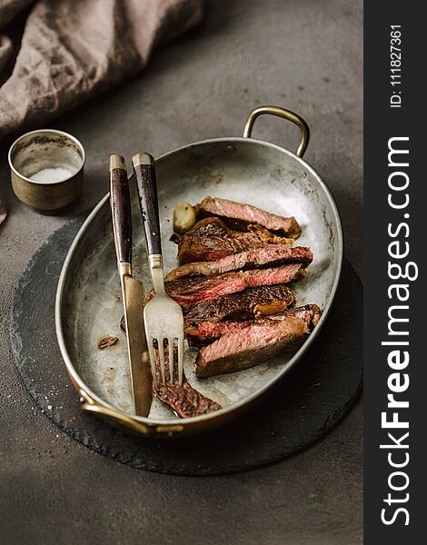 Slices juicy roast beef steak on vintage frying pan close up. Slices juicy roast beef steak on vintage frying pan close up