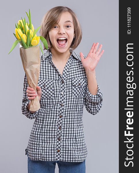 Beautiful girl with bunch of flowers on gray background. Smiling child with bouquet of yellow tulips as a gift. Happy mothers, Birthday or Valentines day. Beautiful girl with bunch of flowers on gray background. Smiling child with bouquet of yellow tulips as a gift. Happy mothers, Birthday or Valentines day.