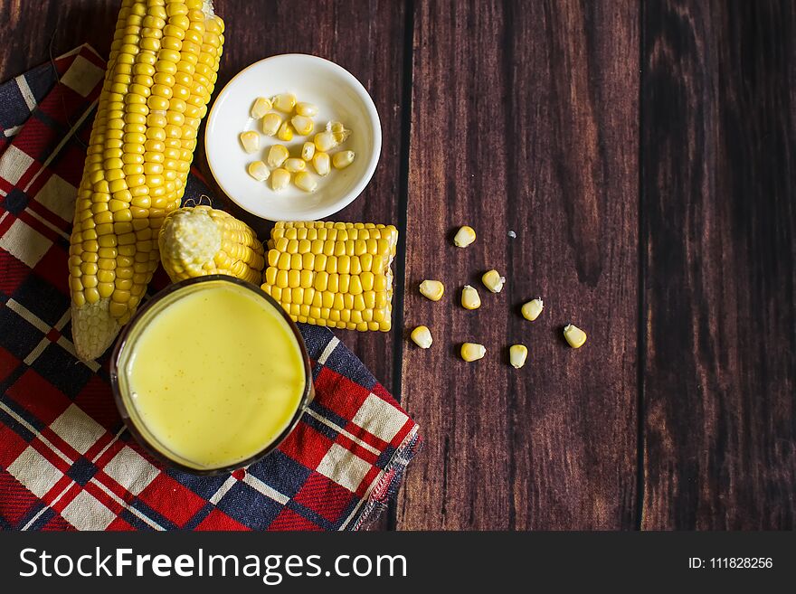 Fresh corn and milk on cobs on wooden table, closeup.