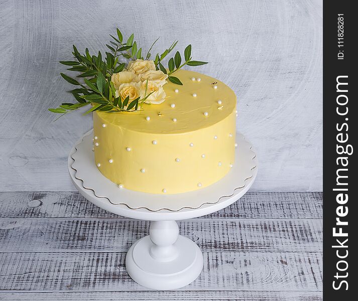 a yellow cream cheese cake with roses and greenery