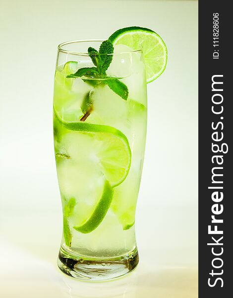 Summer cold drink mojito lime and mint with ice and soda with drops on a glass on a white background