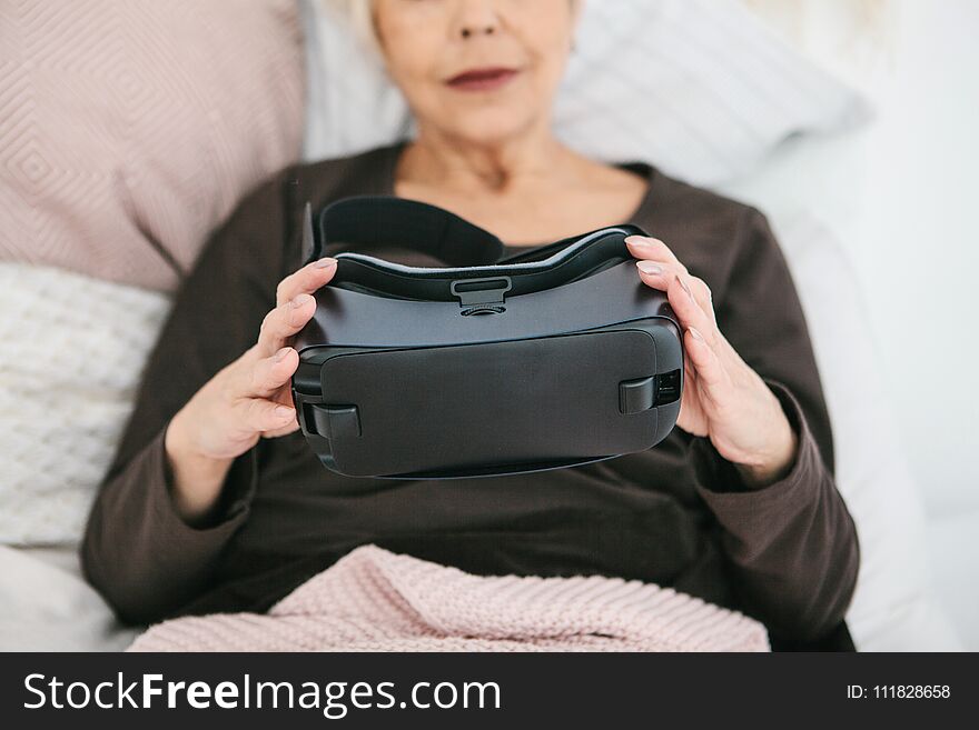 An elderly woman is going to put on virtual reality glasses to use them to immerse in the virtual world. The older