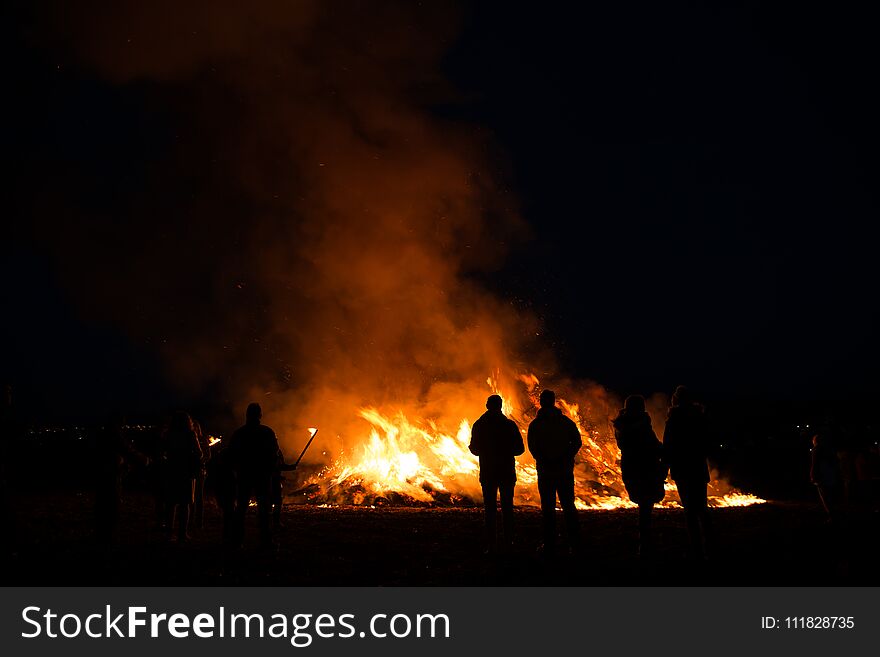 Silhouettes of people in frontof big fire