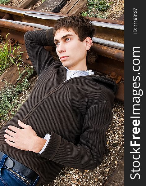 Young man laying on a railway tracks