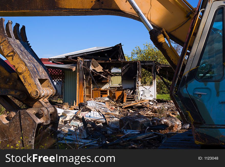 An excavator demolishes a burnt-out house. An excavator demolishes a burnt-out house.