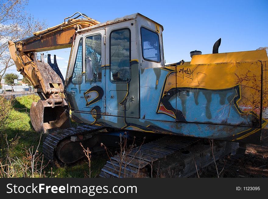A graffitied excavator at a demolition site.