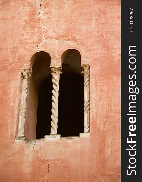 Mullioned window with two lights in a red wall of Gaeta medieval cathedral, southern Italy
