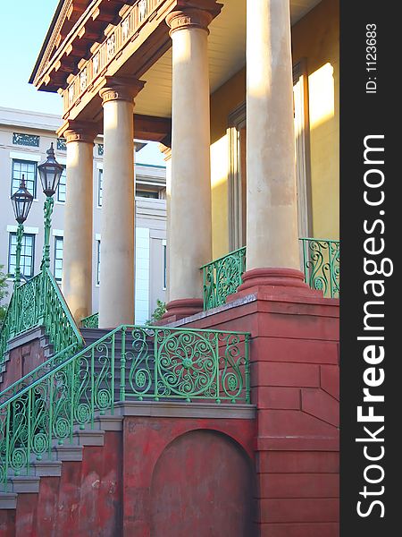 An elegant old building with 4 columns and a detailed stairway