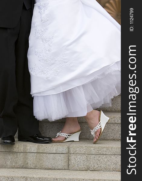 A bride and groom stand toe to toe in their wedding shoes. Closeup. A bride and groom stand toe to toe in their wedding shoes. Closeup.