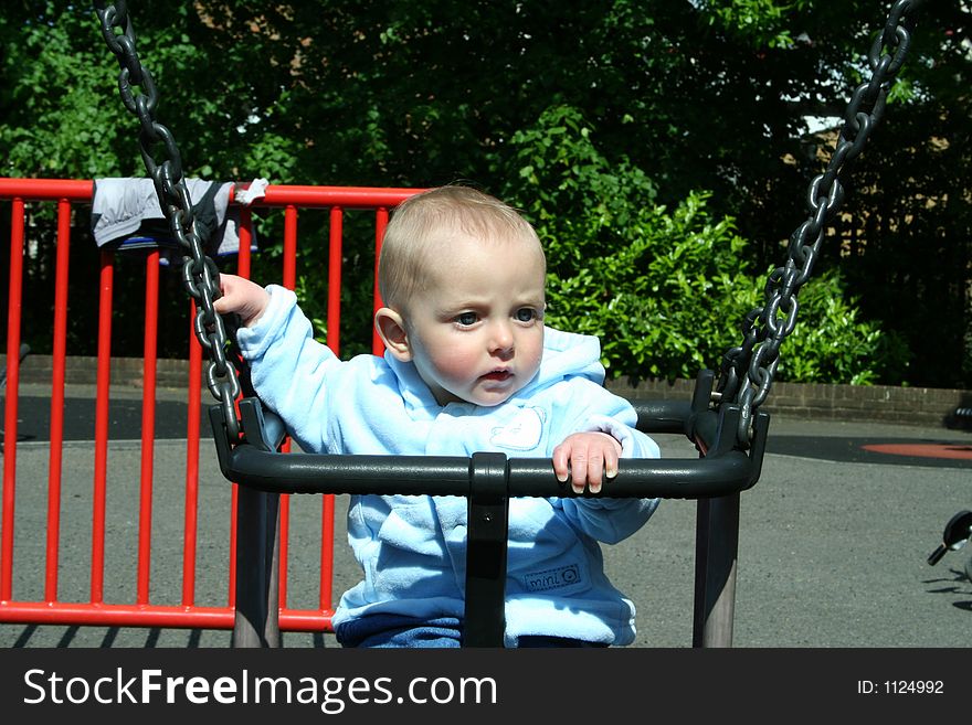 Happy child playing on swing in playground