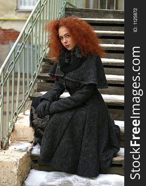 Portrait of the girl with red hair in a black coat