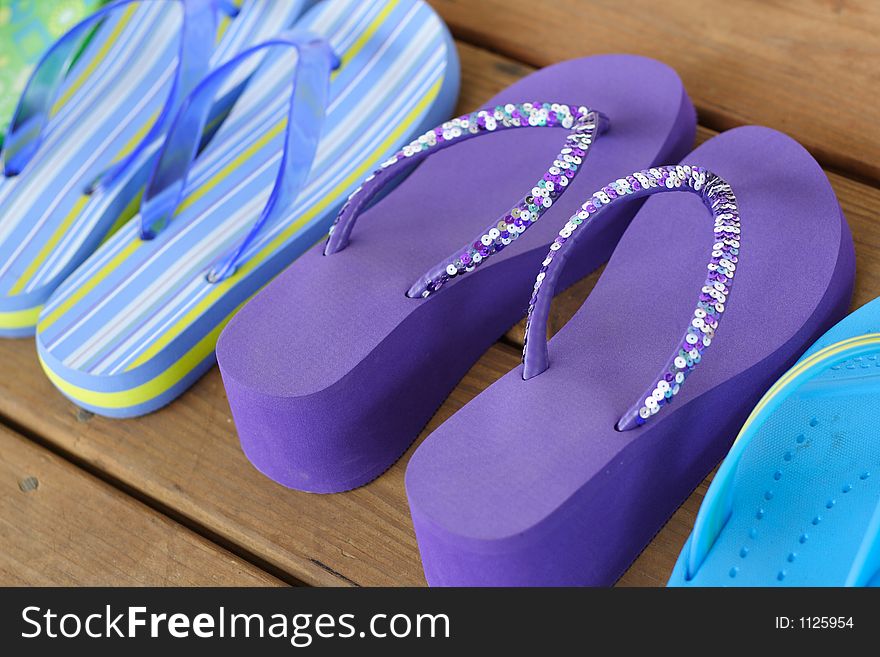 Shot of fancy flip flops lined up on a wooden deck during the summer.