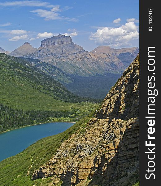 This image of the trail cut into the cliff above the lake with the mountains in the background was taken in Glacier National Park. This image of the trail cut into the cliff above the lake with the mountains in the background was taken in Glacier National Park.