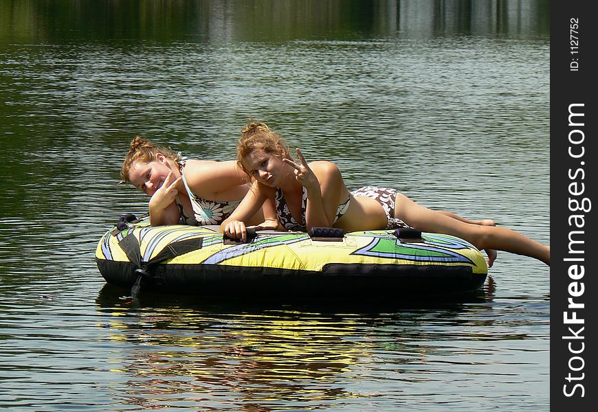 My teenage daughter and her friend relaxing on a tube (and posing) on a lazy ride down the river behind our boat on a beautiful sunny morning. My teenage daughter and her friend relaxing on a tube (and posing) on a lazy ride down the river behind our boat on a beautiful sunny morning.