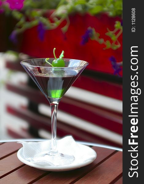 Mint Chocolate Cocktail with green cherry on sword and flowers at blurry background