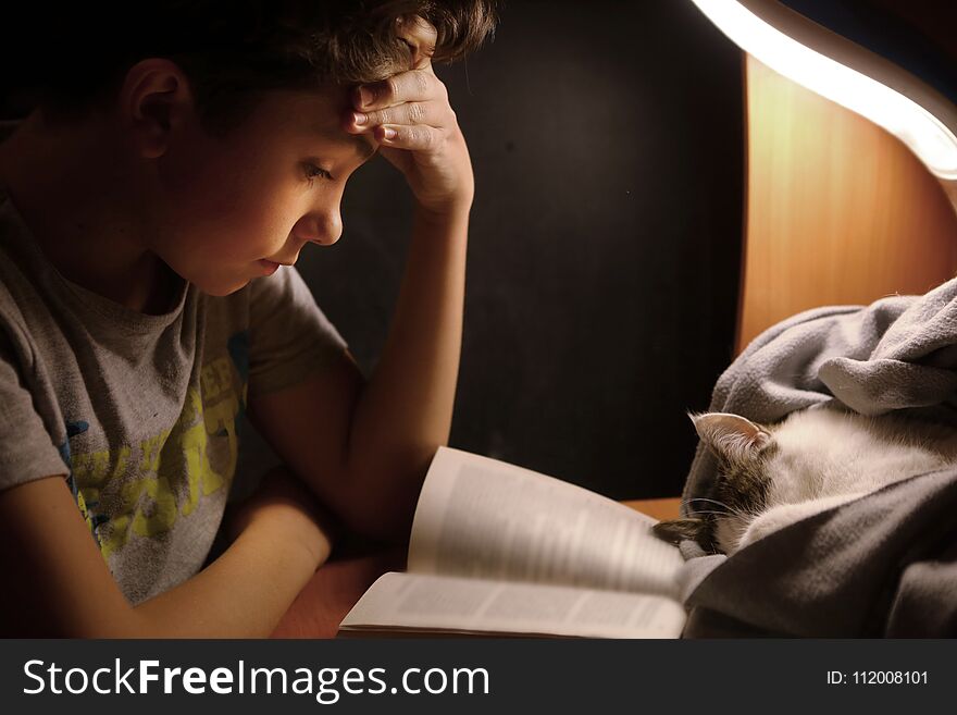 Teenager boy make homework at desk with lamp book