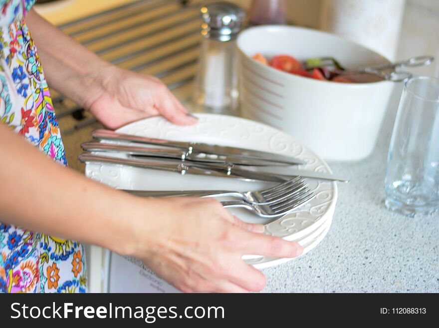 Woman setting table for future guests in the kitchen, the best porcelain. Woman setting table for future guests in the kitchen, the best porcelain