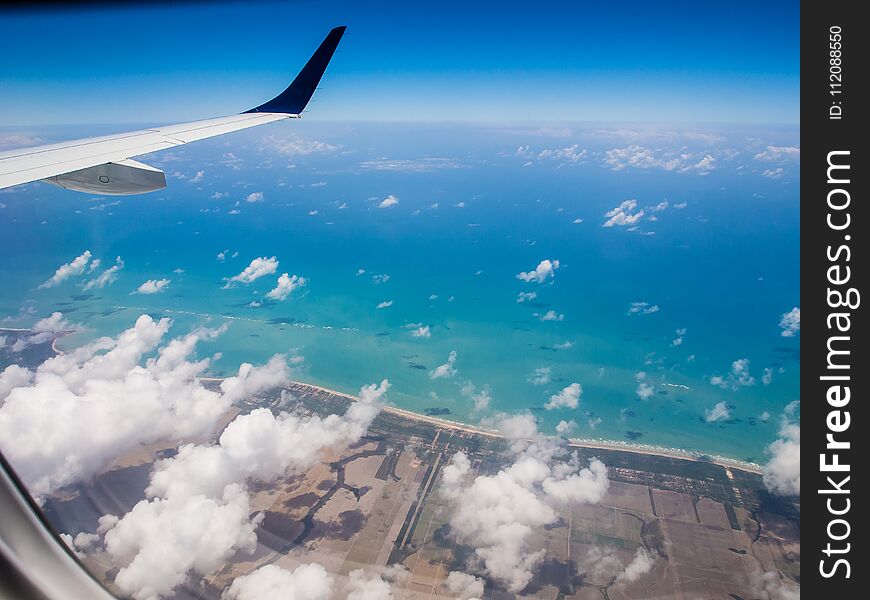 Shot of beach taken from airplane, wing in the corner, high aerial view