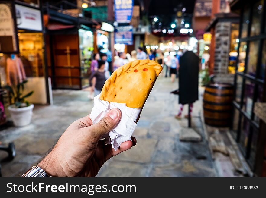 Meat pastry in market, hand held, people blurred in background