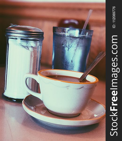 White Ceramic Mug Fill With Coffee Beside Condiment Shaker
