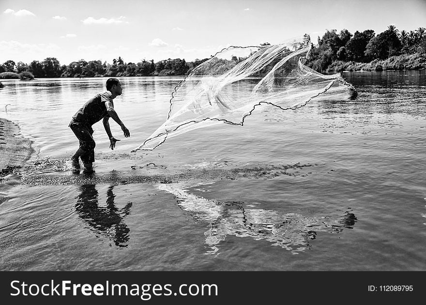 Grayscale Photo of Man Throwing a Fishing Net