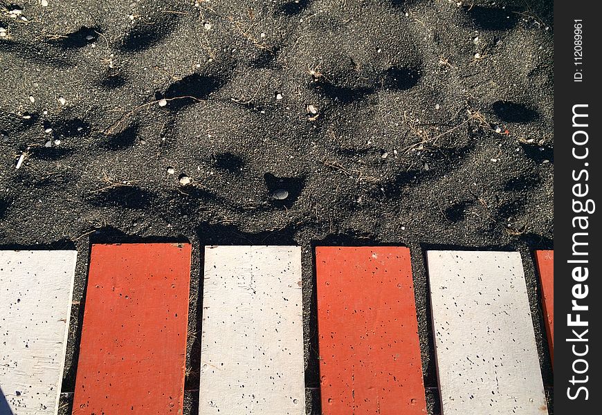 Red and White Metal Planks on Black Sand