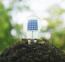 Light Bulb With Solar Cell Inside On Pile Of Soil Over Green Environment Royalty Free Stock Images