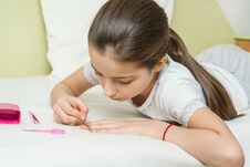 The Girl Is 10 Years Old At Home On The Bed In Her Home Clothes, Nails Her Nails Using Manicure Accessories. Royalty Free Stock Images