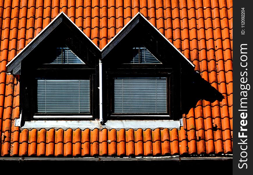 Double Dormers with brown clay pitched roof and metal gutter. metal snow guard and ice breaker. frontal elevation view. strong shadow. summer lights.