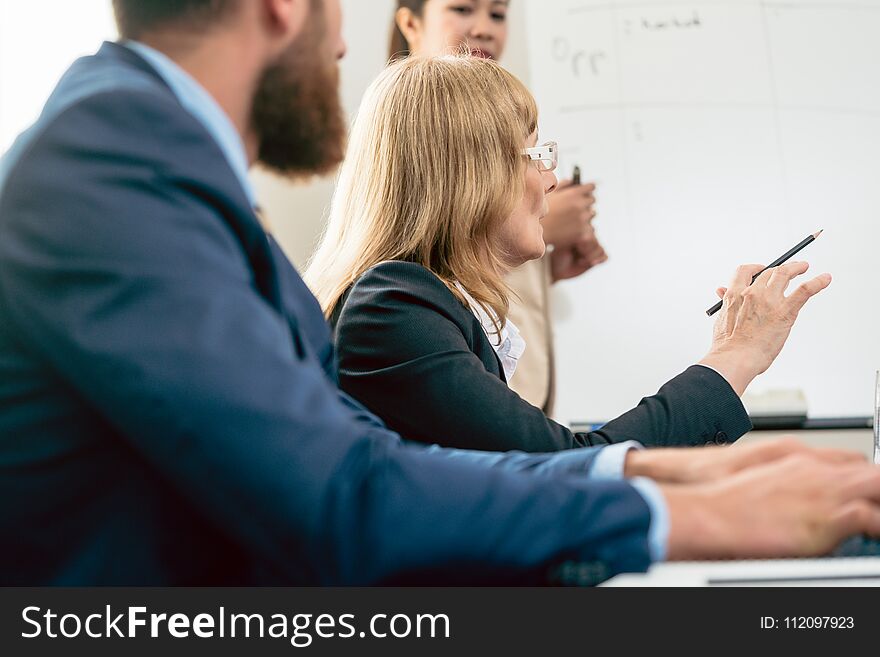 The view of a middle-aged business women presenting her vision and opinion about a project during a decision-making meeting in the conference room. The view of a middle-aged business women presenting her vision and opinion about a project during a decision-making meeting in the conference room