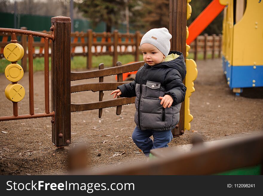 Little boy dressed in warm clothes walking on the playground